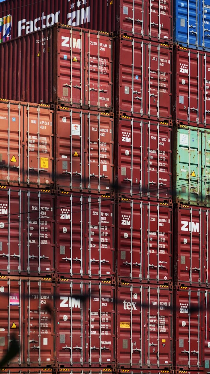 service-04 Vertical shot of colorful, stacked shipping containers at a bustling cargo port.