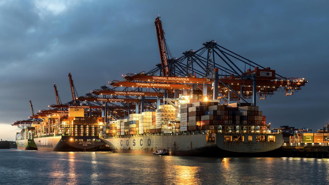 service-05 Illuminated container ships and cranes at Hamburg port during nighttime, showcasing global shipping.